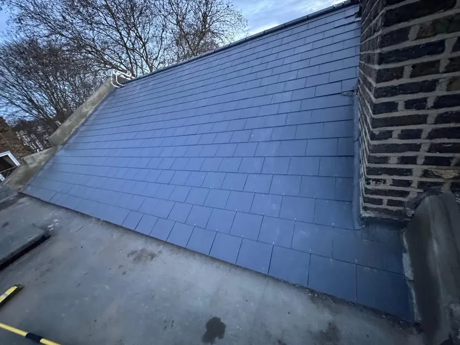 Blue-grey slate-effect roof beside a brick chimney and flat roof