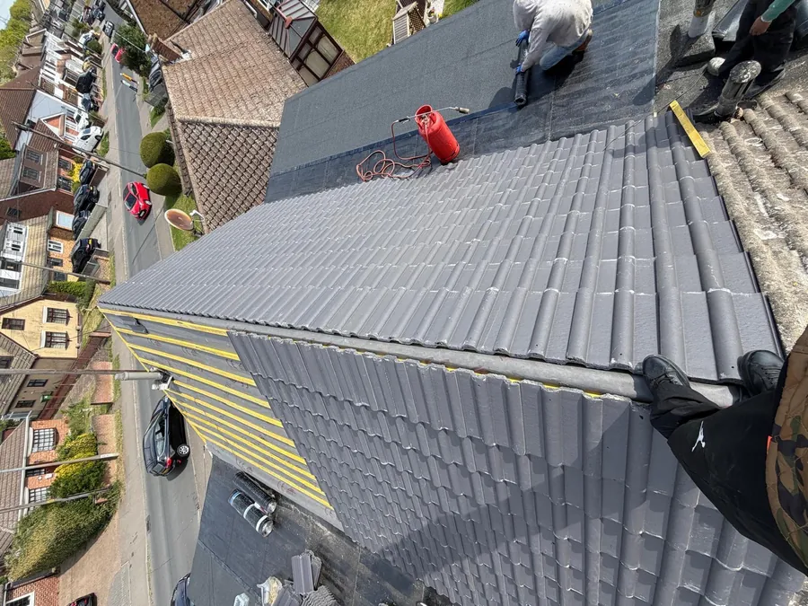 Grey interlocking tile roof during ridge installation