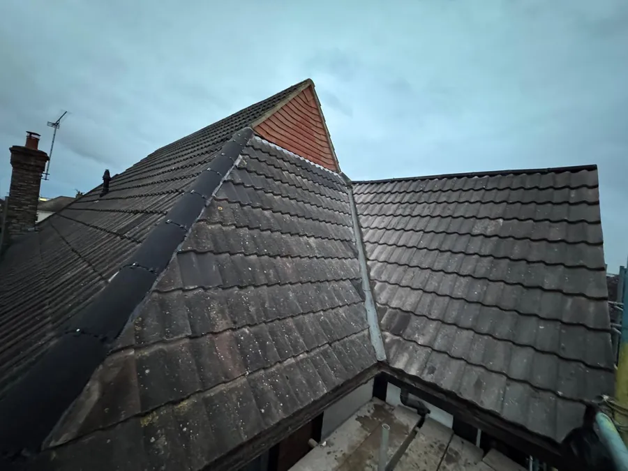 Hip junction between grey tiled slopes and a red gable