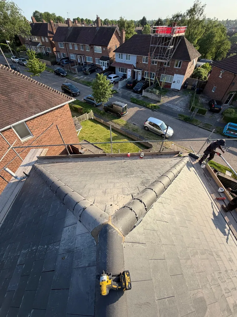 Hip junction and grey tile courses above scaffold and houses