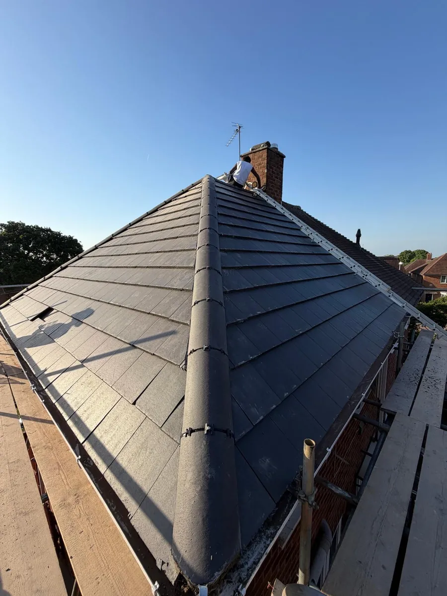 Slate-effect hip roof with scaffolding and chimney behind