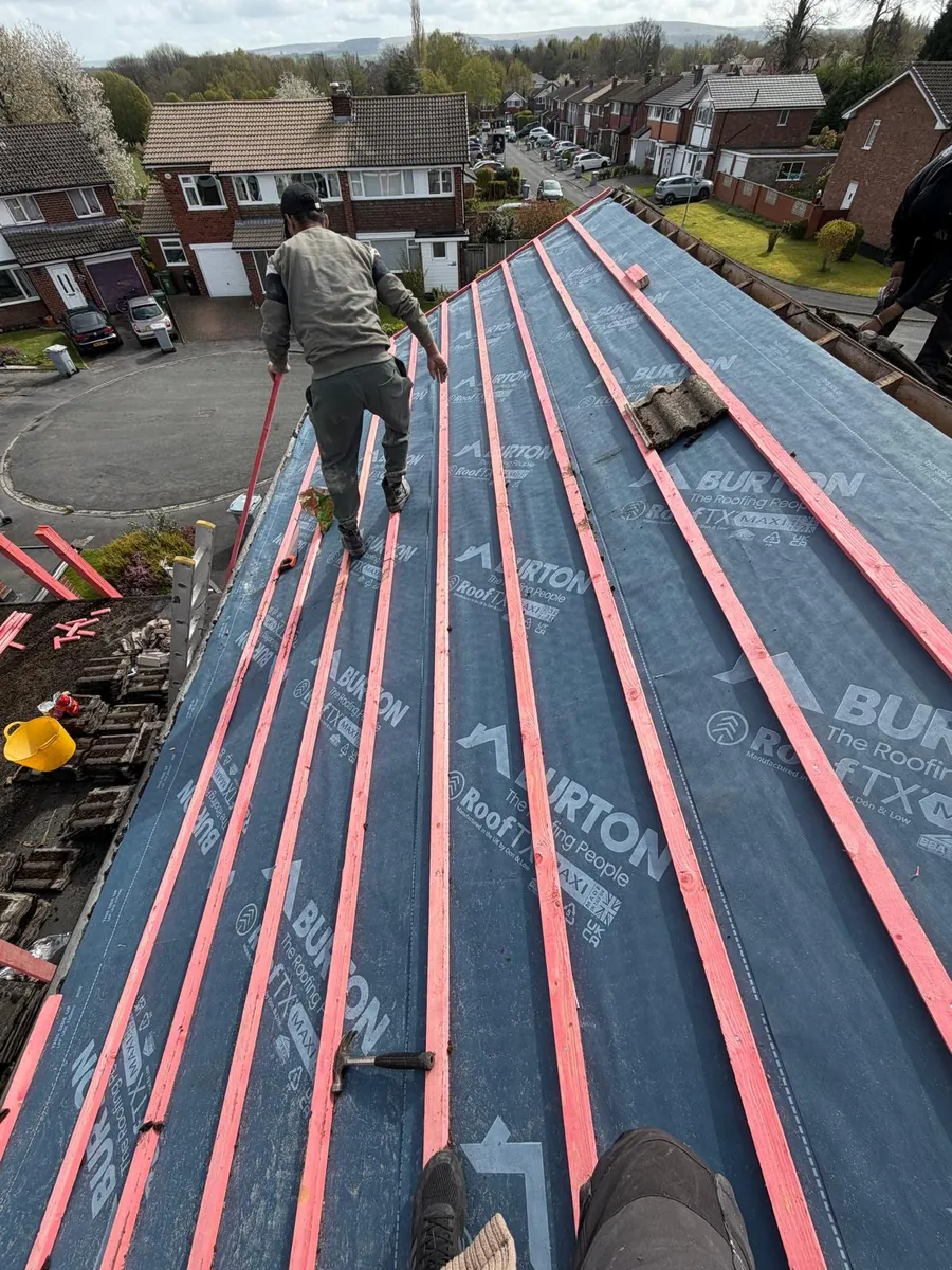 Roofer standing on a membrane-covered roof with red timber battens
