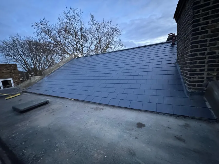 New blue-grey tiled slope above a flat roof with a chimney