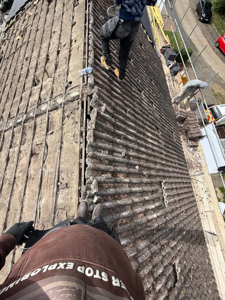 Old roof tiles being stripped to reveal battens and underlay