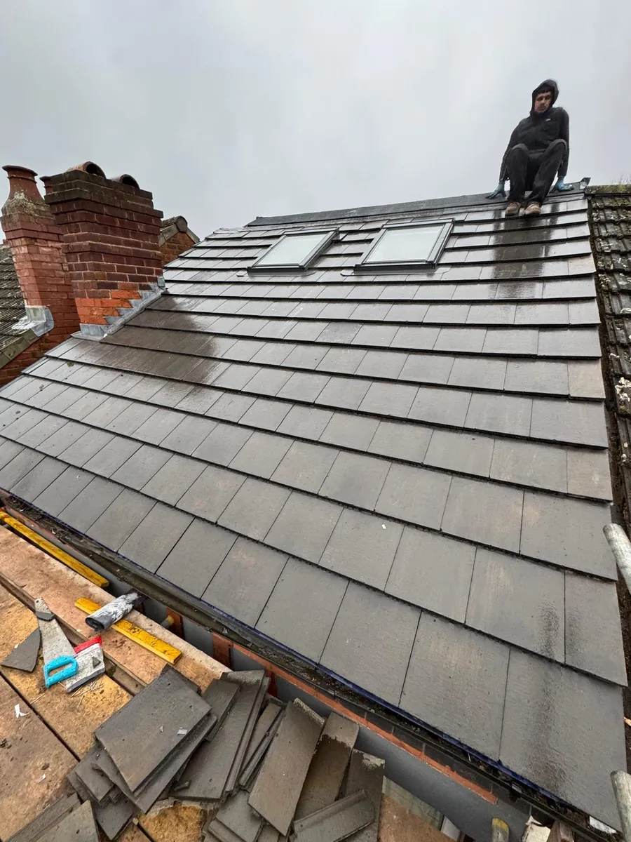 Roofer at the ridge above new tiles and two rooflights