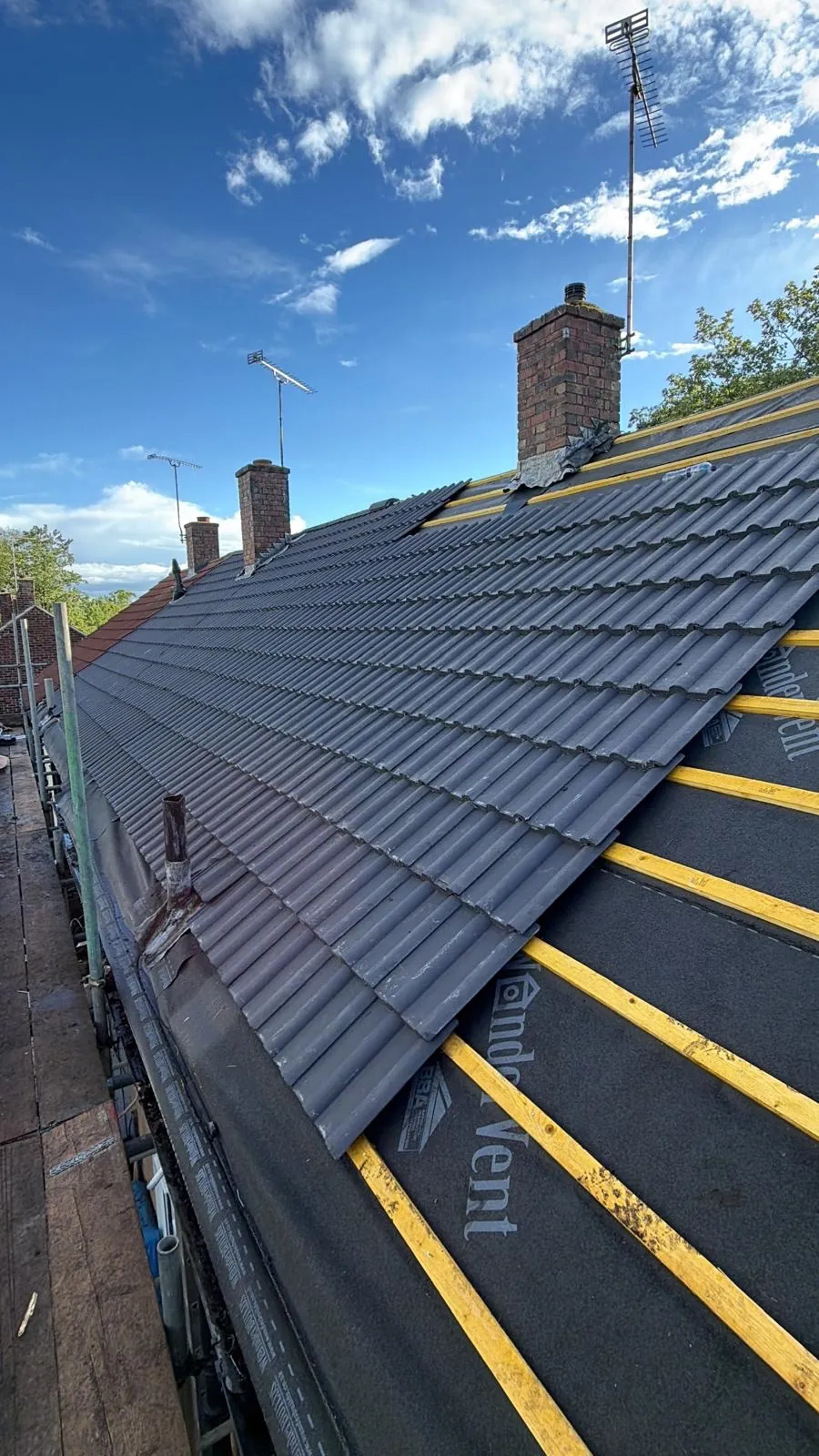 New grey tiles meeting exposed membrane and yellow battens